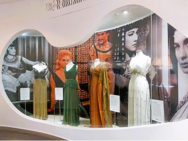 A photo of a museum exhibition display of four dresses