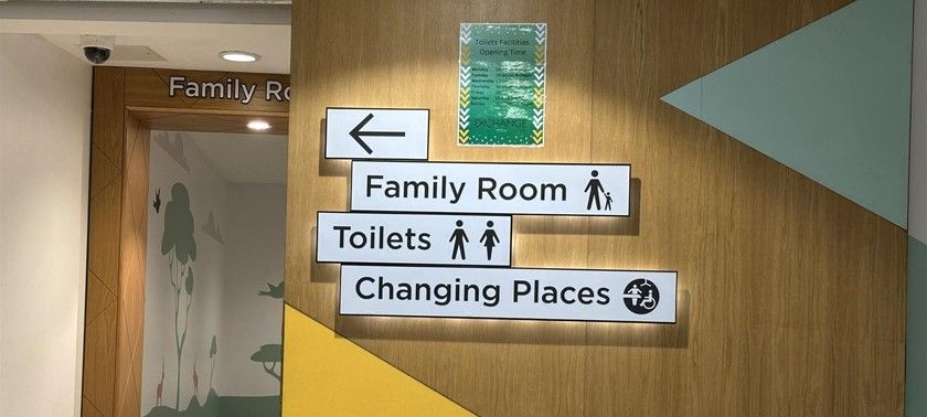 A photograph of signage pointing to Family Room, Toilets, Changing Places