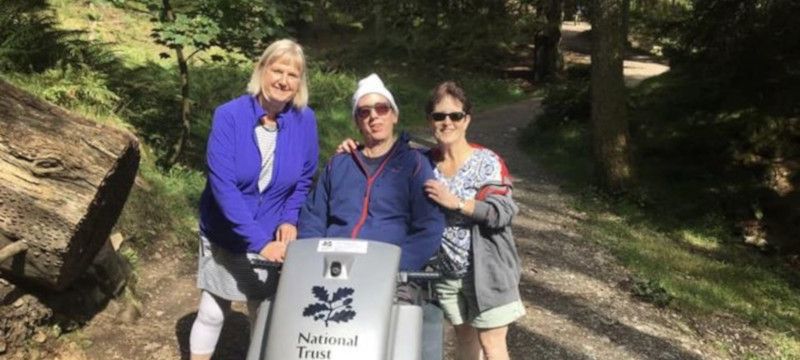 Photo of a man using an off-road scooter on a woodland path.